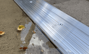 Gros plan d'un joint de seuil en aluminium de résistance industrielle arrêt l'eau et les feuilles